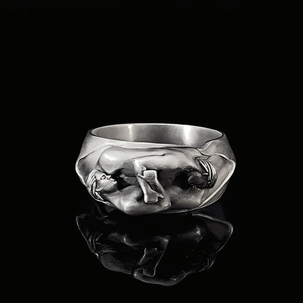 Silver ring with a detailed two male sculpture design on a black background