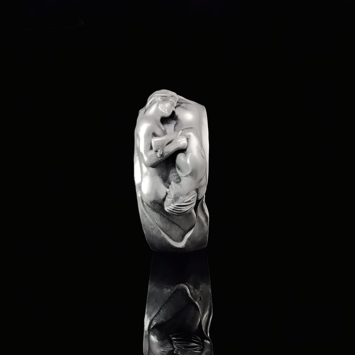 Sterling silver ring with a detailed artistic male couple sculpture design on a black background