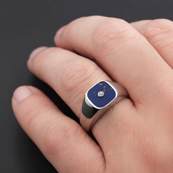Close-up of a hand wearing a ring with a navy blue and silver design on a dark background