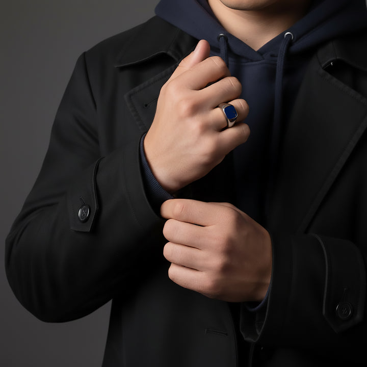 Person wearing a black coat, blue hoodie and silver ring 
