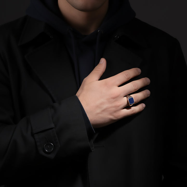 Hand wearing a sterling silver blue stone ring on a dark background