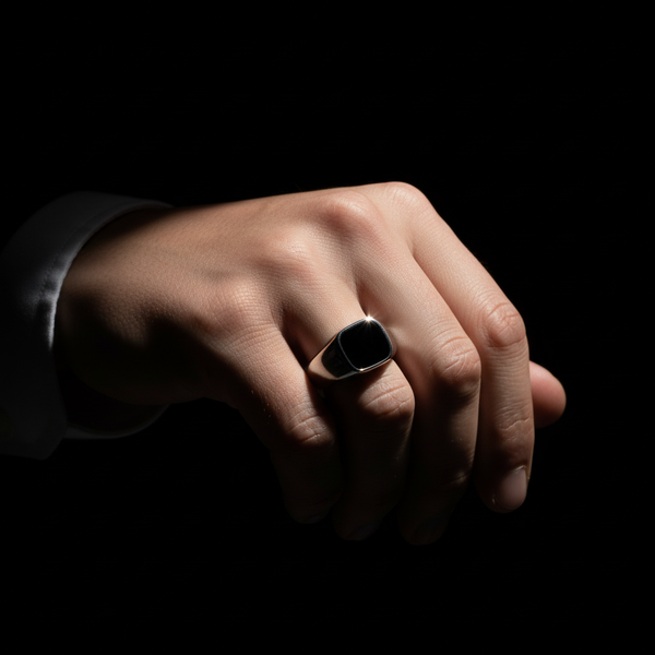Hand wearing a signet ring on a black background