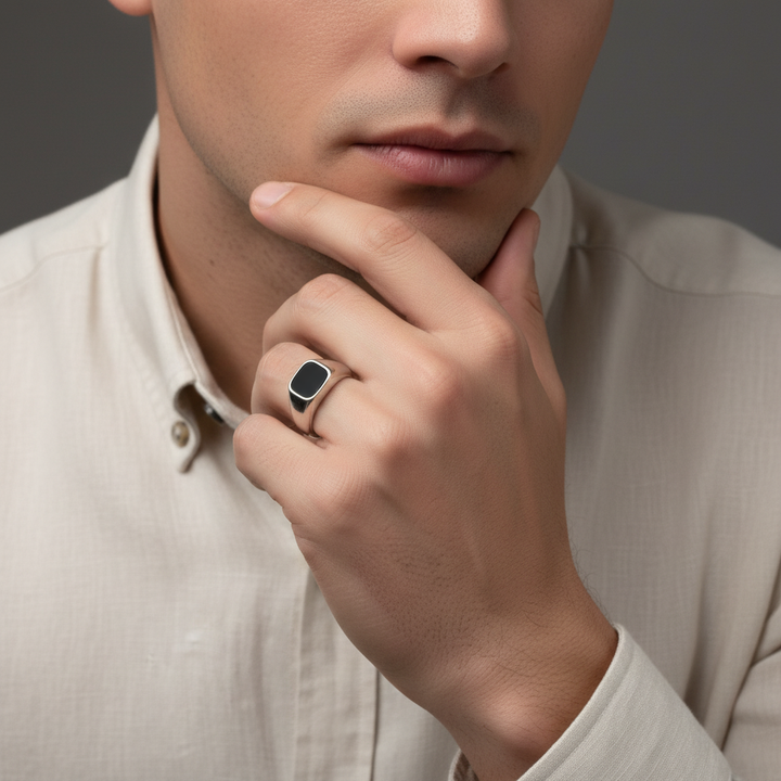 Man wearing a signet ring on his finger, with a neutral background