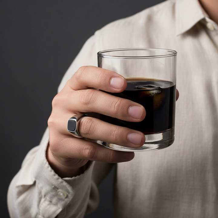 Hand wearing a sterling silver ring on a dark background