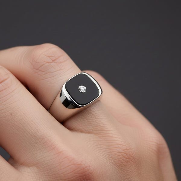 Black square stone ring with a diamond on a hand against a dark background